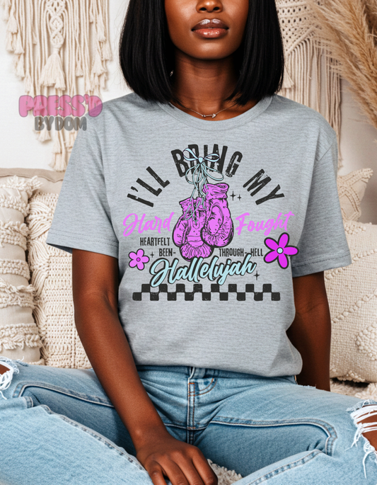 Woman wearing white graphic tee with pink boxing gloves that reads “I’ll Bring My Hard-Fought Hallelujah” – faith-based shirt by Press’d by Dom