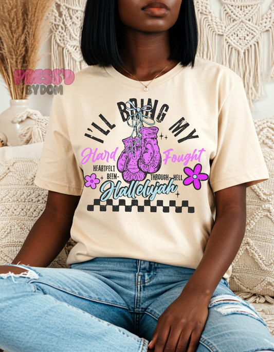 Woman wearing white graphic tee with pink boxing gloves that reads “I’ll Bring My Hard-Fought Hallelujah” – faith-based shirt by Press’d by Dom