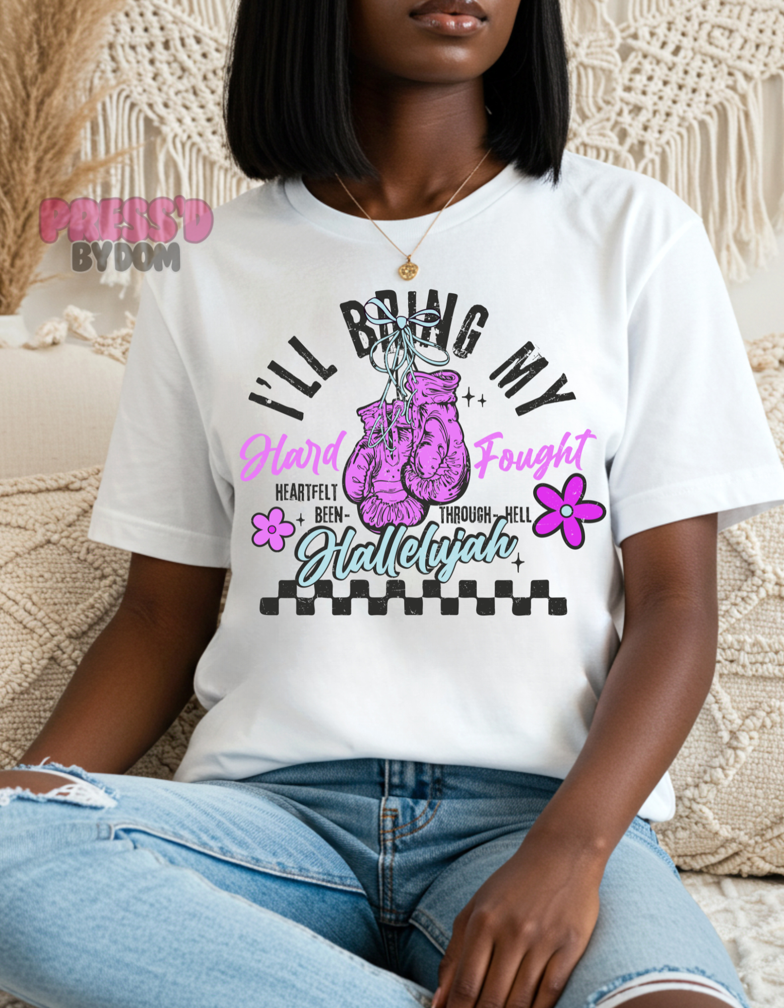 Woman wearing white graphic tee with pink boxing gloves that reads “I’ll Bring My Hard-Fought Hallelujah” – faith-based shirt by Press’d by Dom